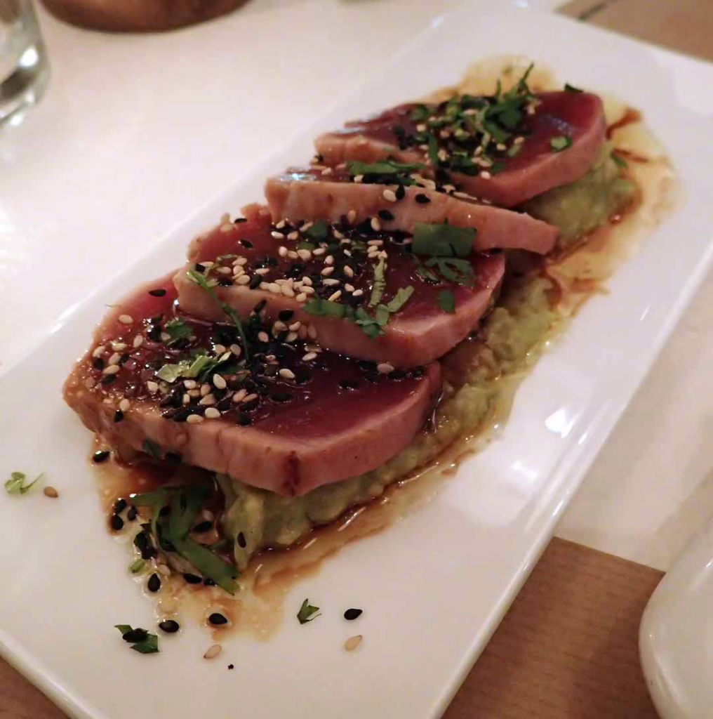 Rare slices of tuna on avocado mash with sesame seeds on top at Bar Lobo Barcelona