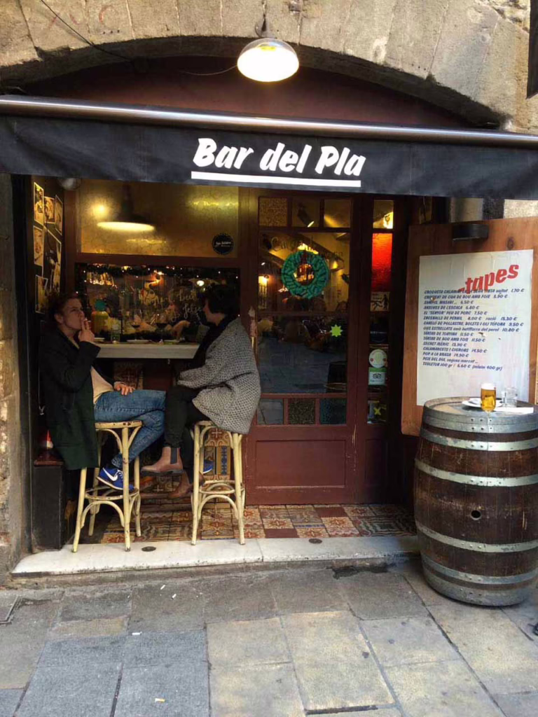Two customers sitting at the sole outdoor table in front of Bar del Pal in Barcelona
