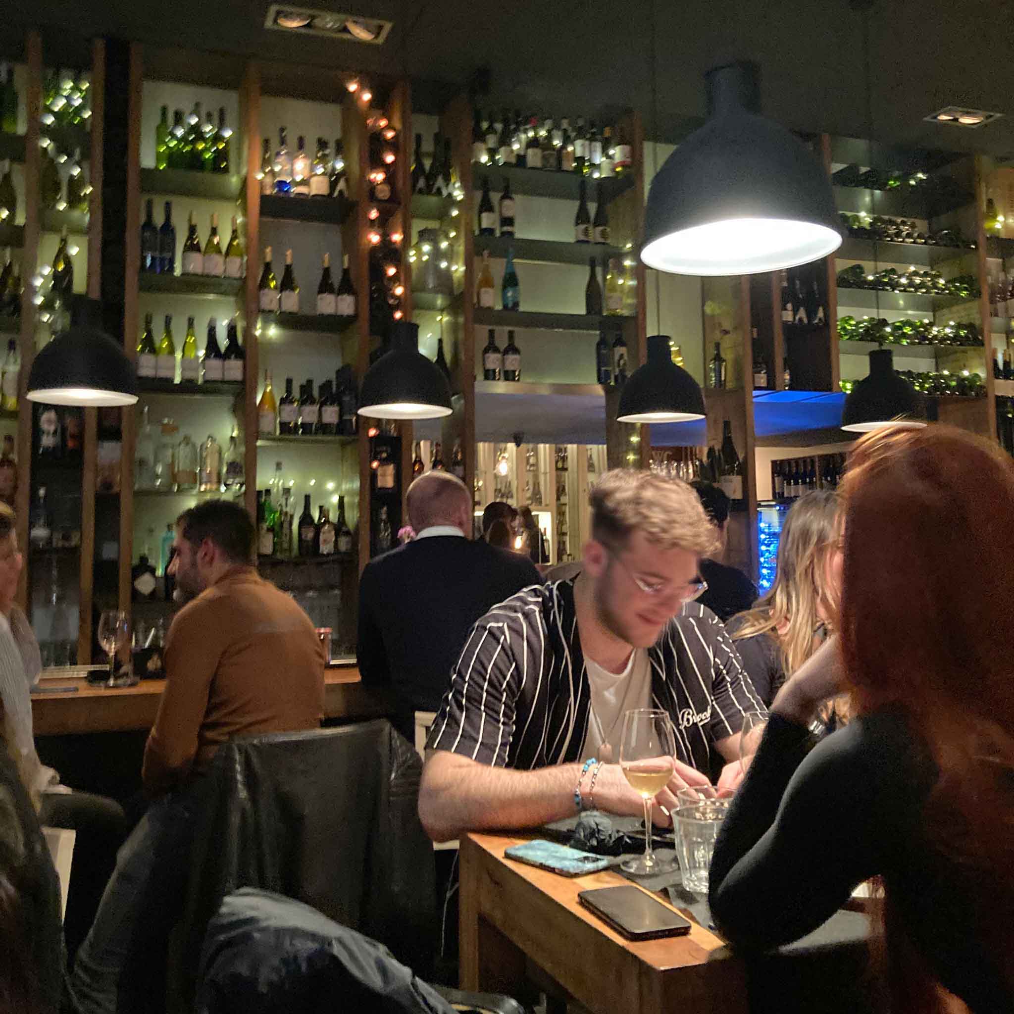 diners with a wall of wine behind them at Eldiset Bar in Barcelona
